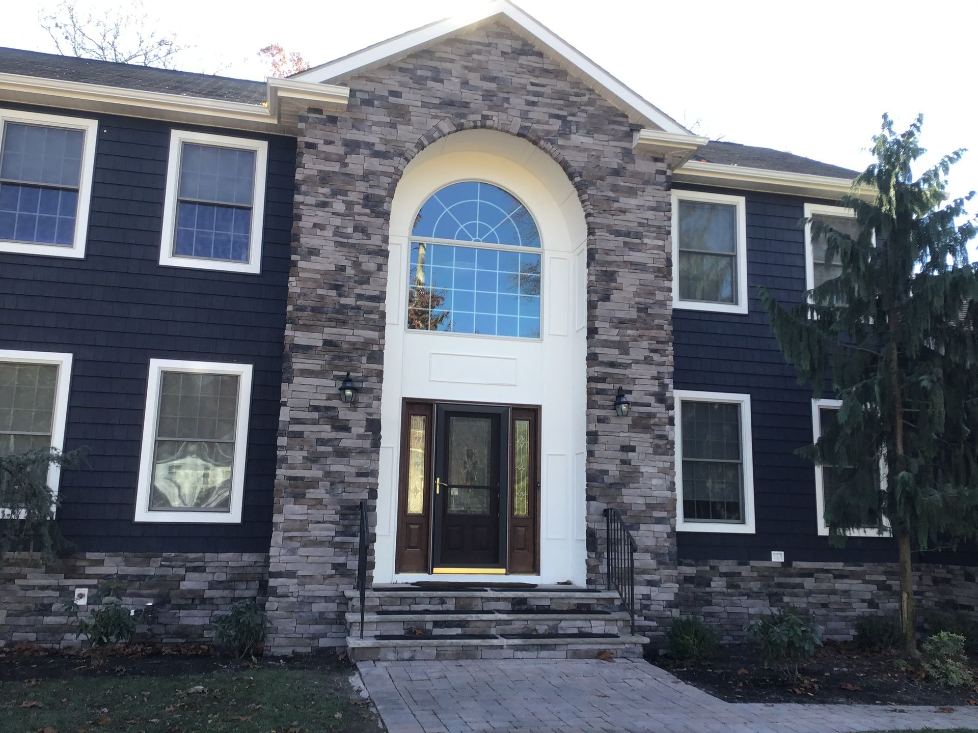 Superior Siding project — Custom entry · stone veneer columns · navy shake siding